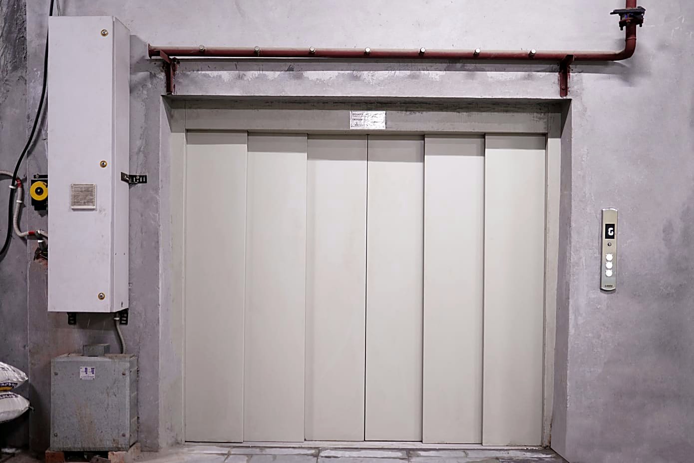 Span car elevator landing — bi-parting steel doors in a concrete surround with Span controls.