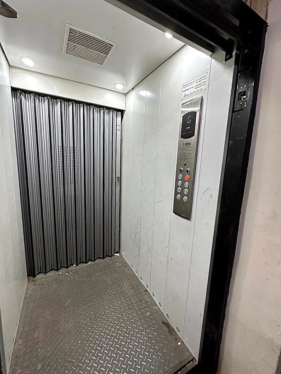 Span Bhāravāha goods-cum-passenger lift — telescopic steel gate, chequered-plate floor and Span control panel.